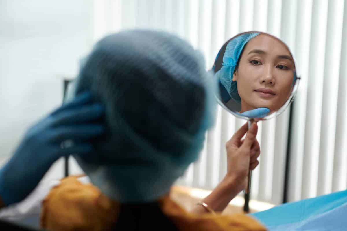 Patient looking in the mirror post cosmetic procedure.